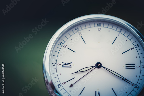 Close-up of a vintage clock on a beautiful green background. Old watch as a symbol of passing time. Concept on the theme of history, nostalgia, old age.