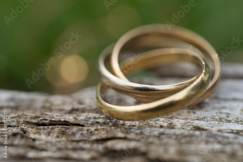 Close-up of a ring with three rings on wooden background. Wedding jewelry in gold, white gold and rose gold. macro shot with selective focus