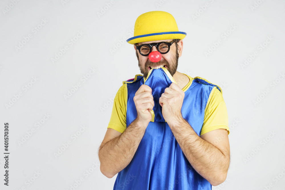 A clown in a bright blue and yellow suit bites his tie from fright