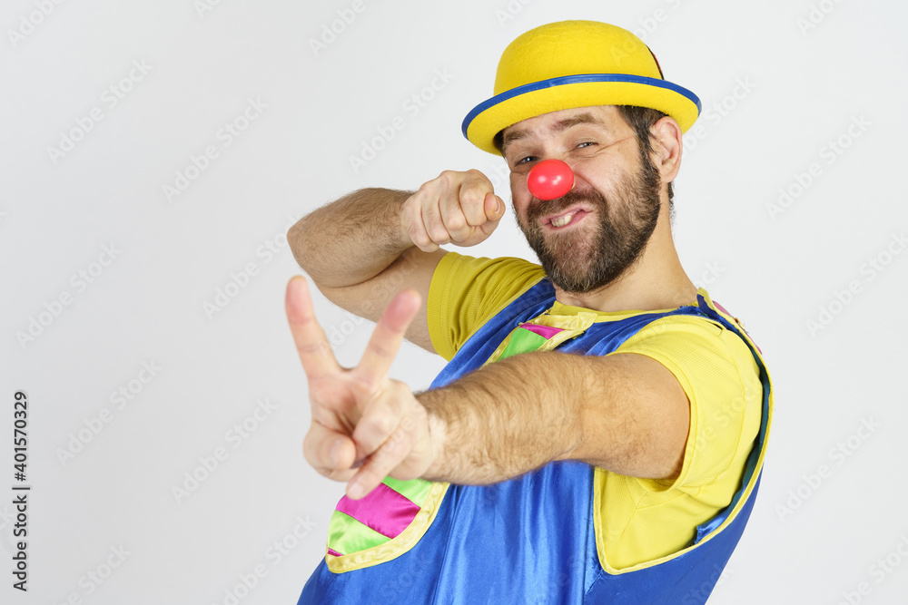 A clown in a bright blue and yellow suit shows a slingshot with his hands - aims A clown in a bright blue and yellow suit shows a slingshot with his hands - aims
