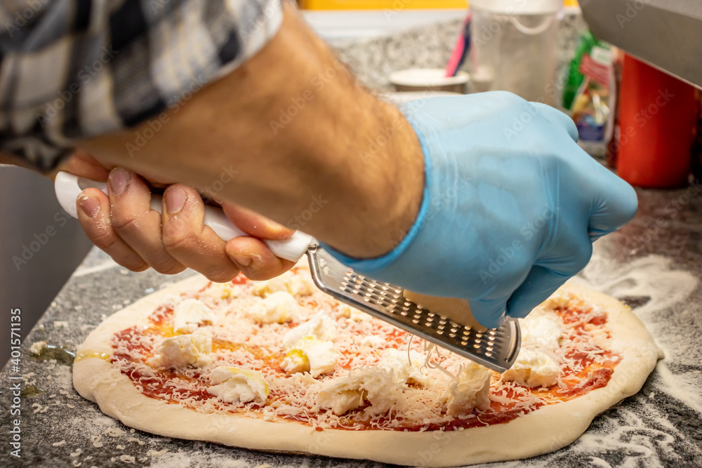 A man making a margherita pizza in a local pizza and gyros restaurant