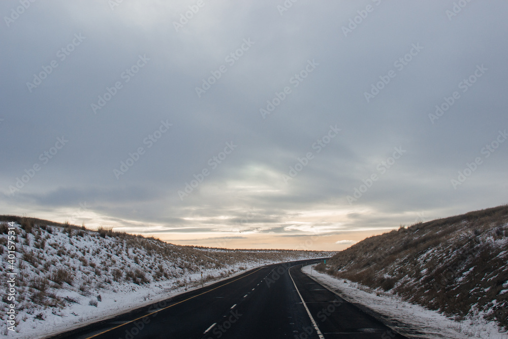 Winter highway among mountains covered with snow along which cars and trucks travel. Montana, USA, 01-18-2020 Winter highway among mountains covered with snow along which cars and trucks travel. Montana, USA, 01-18-2020