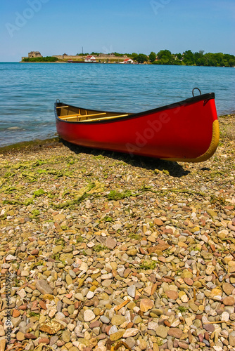 Red Canoe on Rocky Shore with Fort Niagara in the Background at Queens Royal Park, Niagara On The Lake, Ontario, CAN