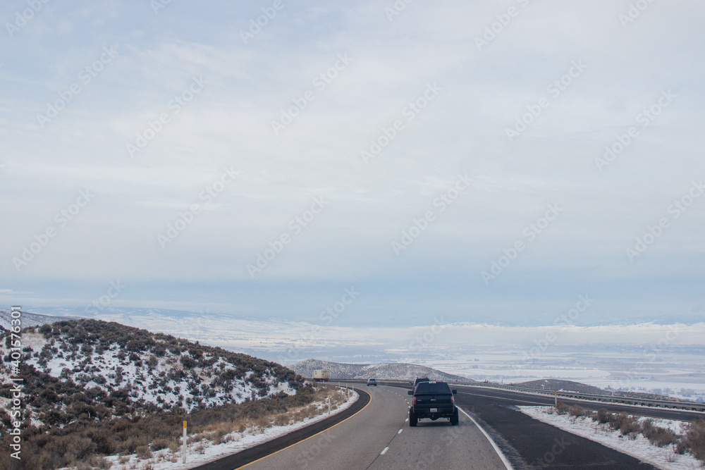 Winter highway among mountains covered with snow along which cars and trucks travel. Montana, USA, 01-18-2020
