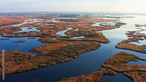 Top view of the beautiful Samarskie Plavni on the Dnieper with a village nearby in the warm evening light. Aerial UHD 4K drone realtime video, shot in 10bit HLG and colorized