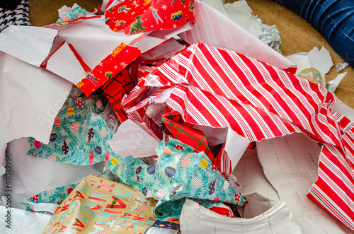 Discarded Christmas wrapping paper thrown in a big pile on the floor having been ripped off presents.