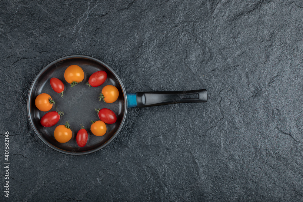 Wide angle photo of Colorful cherry tomatoes in the pan on black background Wide angle photo of Colorful cherry tomatoes in the pan on black background
