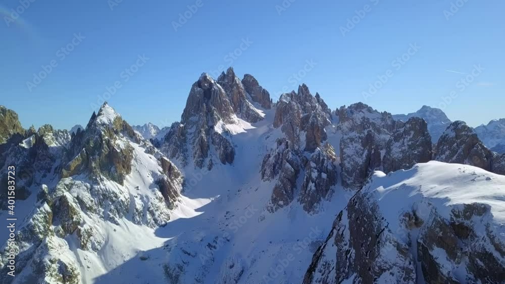 Daytime landscape of snow-capped mountain peaks of Dolomites in Italy, Europe. In a sunny winter day, a drone shooting and slowly advancing to the steep Dolomites Daytime landscape of snow-capped mountain peaks of Dolomites in Italy, Europe. In a sunny winter day, a drone shooting and slowly advancing to the steep Dolomites