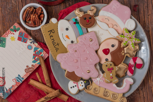 Christmas gingerbread cookies on vintage plate, hot chocolate, with color lights on rustic table.