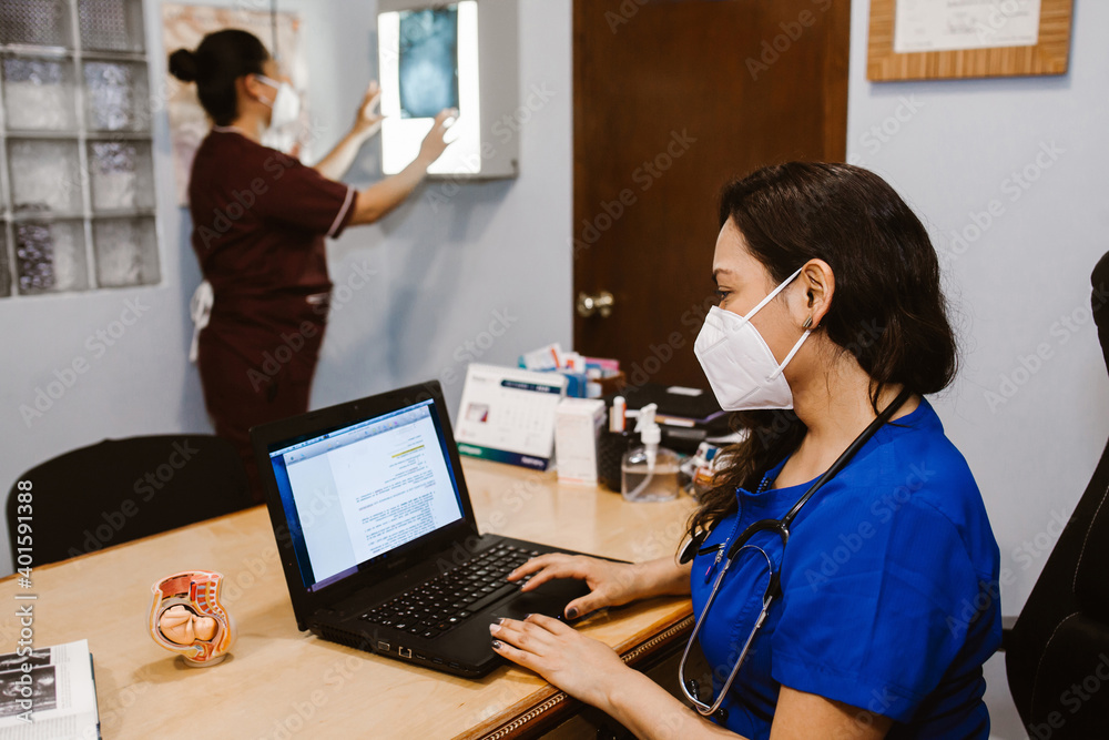 Mexican female doctor working while sitting at desk in front of laptop in a Mexican hospital