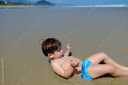 menino brincando em praia vazia e dia ensolarado  photo