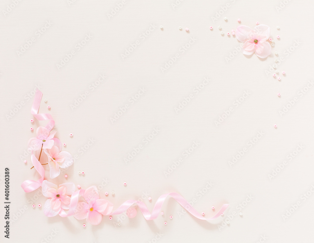 Frame from gentle pink flowers and ribbon on background light beige backgroun. Artificial pink flowers in form of frames. Copy space