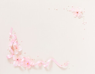 Frame from gentle pink flowers and ribbon on background light beige backgroun. Artificial pink flowers in form of frames. Copy space