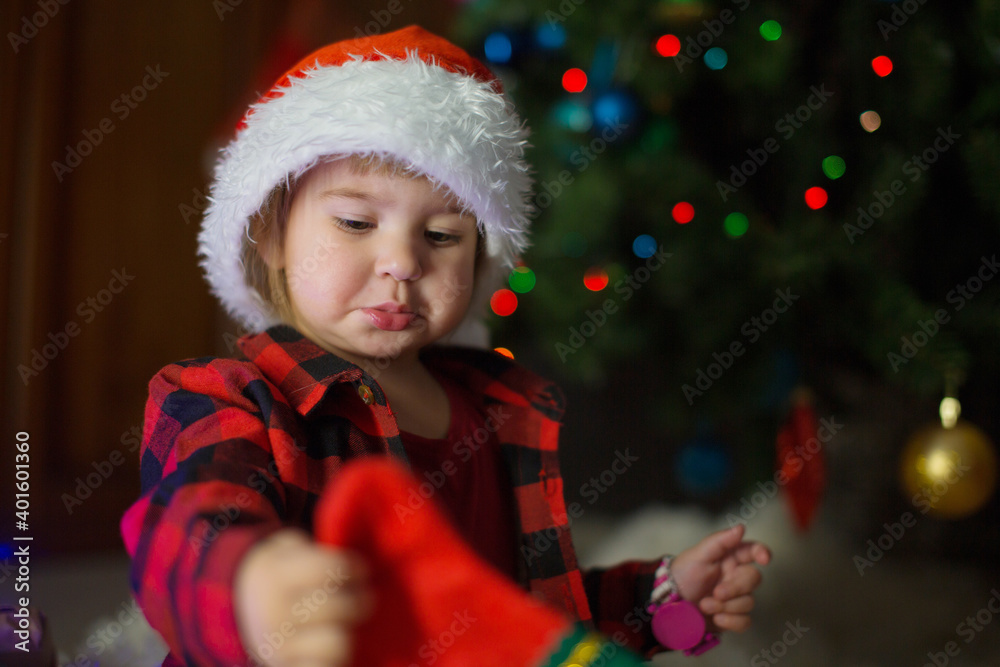 a child in red clothes is sitting waiting for the new year. the concept of celebrating Christmas at midnight. holiday costume