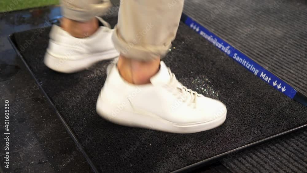 Person rubs white sneakers on sanitizing mat to disinfect
