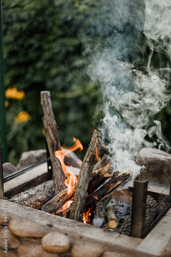 Fototapeta premium Bonfire lighted from wood in the grill at their summer cottage. Bright flame from the fire.