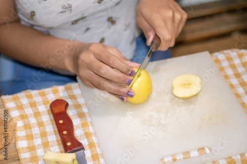 Cutting apple slices. Ingredients for making apple strudel. Latina cuts a yellow apple in half. 