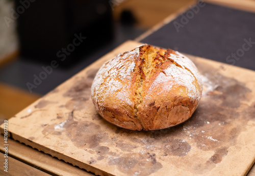 Fresh baked sourdough bread on baking stone. Ingredients: kamut 80%, sourdough starter 10%, baking-malt, all-purpose flour. Homemade rustic bread loaf. Selective focus with defocused table.
