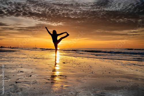 Obraz na płótnie yoga at sunset on the beach. woman is doing yoga and enjoying life on the sea w salonie