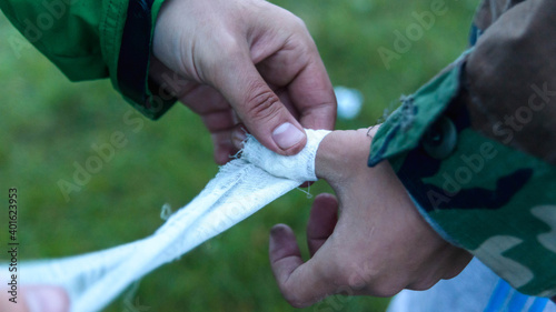 Hands close-up of two men on a hike. Bandaging a bruised finger with a bandage.