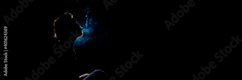Colored silhouette of a smoking man on dark background. Banner panoramic. Copy space for text message.