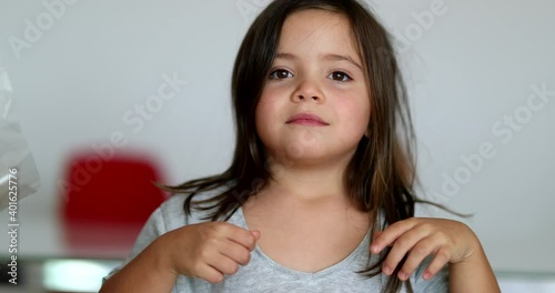 Little girl grimacing to camera sticking tongue out. Child teasing