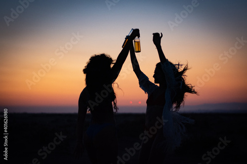 Silhouettes of women partying and dancing at desert music festival