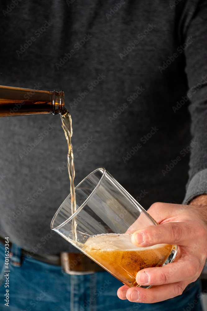 Man serving a craft beer in a wide glass Decanting the beer in a glass. Waiter serving a glass of homemade beer at home. Selected focus. Bottom with bokeh. Close up view. Man serving a craft beer in a wide glass Decanting the beer in a glass. Waiter serving a glass of homemade beer at home. Selected focus. Bottom with bokeh. Close up view.