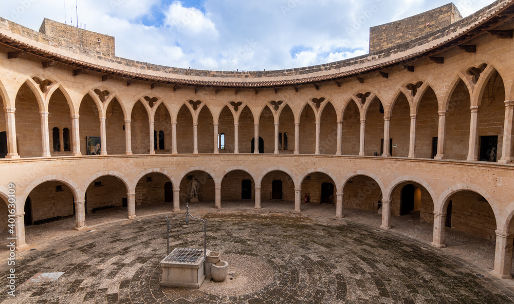 Arcades of the inner courtyard of Bellver castle with a water well in the middle in Mallorca, Spain