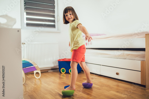 Flat feet correction exercise. Girl walking over spiked half balance massage balls photo