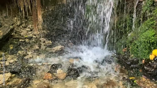 Slow-motion footage of a forest waterfall with clean, clear drinking water on a sunny summer day