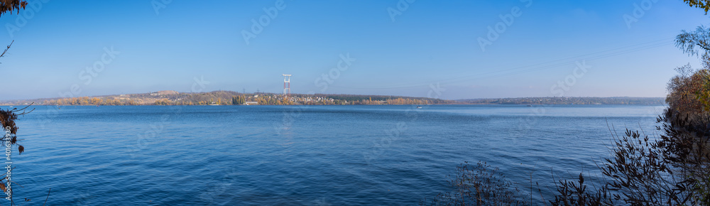 Panorama. Beautiful natural landscape on the bay of the Dnieper river and a green island on a blue sky background