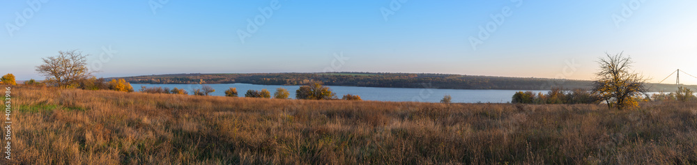 Panorama. Beautiful autumn landscape view of the Dnieper river with a green island on the blue sky background Panorama. Beautiful autumn landscape view of the Dnieper river with a green island on the blue sky background