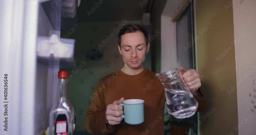 Man opening refrigerator at home and drinks a water, he has a thirst Man opening refrigerator at home and drinks a water, he has a thirst