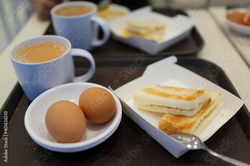 Toasted bread with half boiled egg served with a cup of milk tea, Asian breakfast.