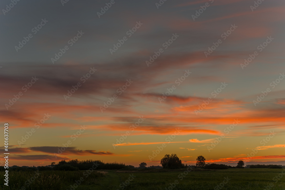 Meadow and colorful clouds in the sky after sunset