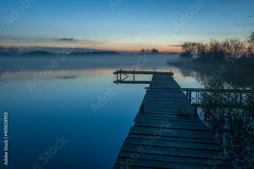Footbridge on the lake and evening fog