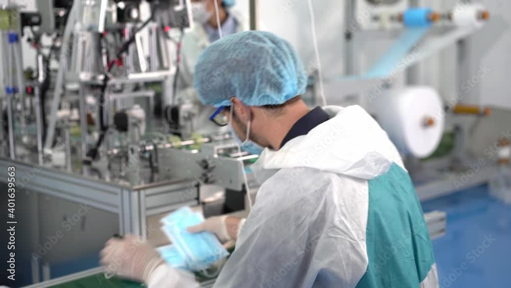 Employees in a mask factory Checking the quality of products on modern industrial machines. Dust and Virus Mask Factory Employees in a mask factory Checking the quality of products on modern industrial machines. Dust and Virus Mask Factory