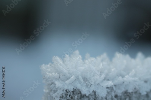 Snow crystals on the surface of a wooden column close-up