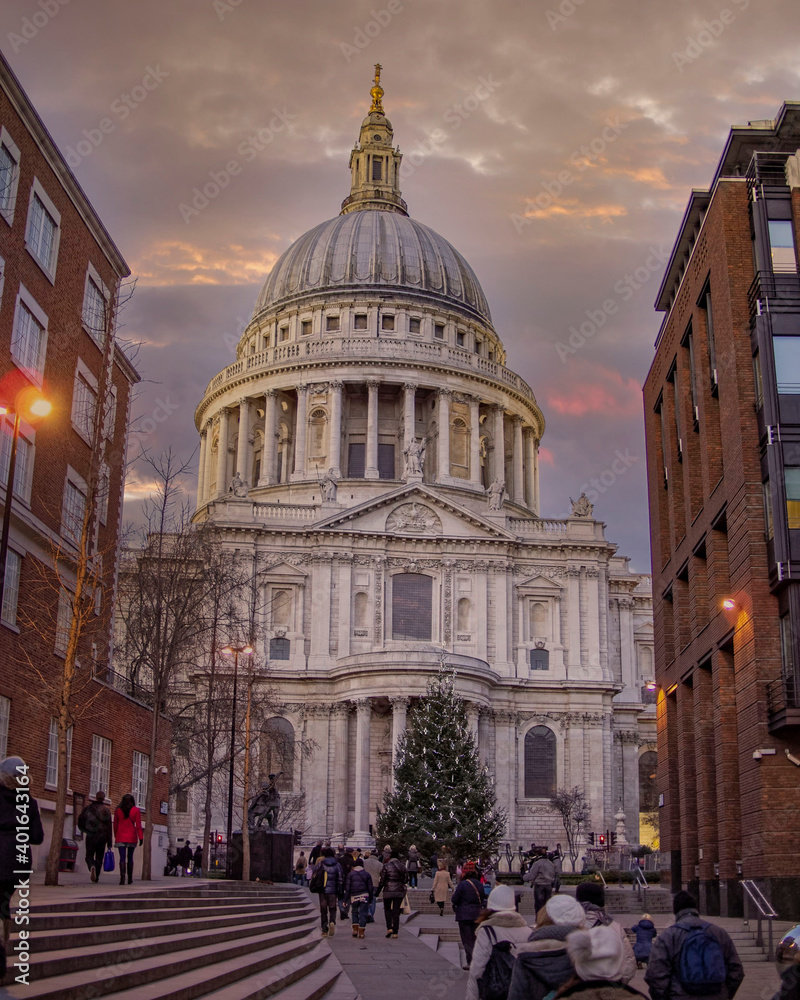 tourists and Christmas tree in front of St Paul's cathedral under impressive sky, London UK