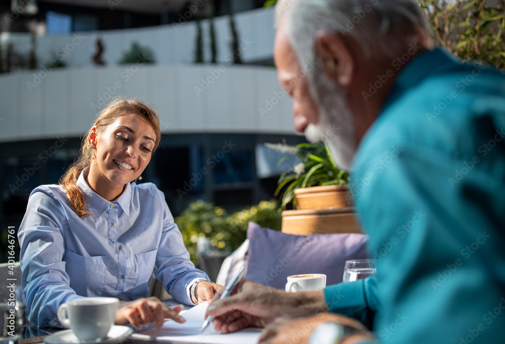 Mature man signing contract with businesswoman