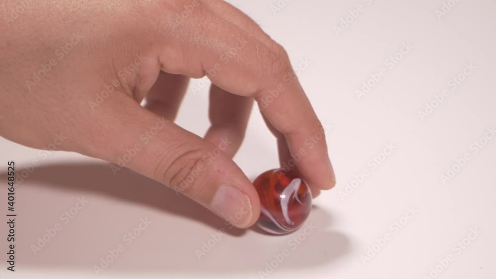 Un uomo gioca con una biglia colorata Un uomo gioca con una biglia colorata
