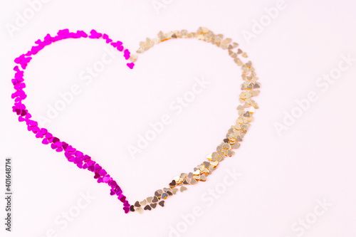 Happy Valentine's Day. Heart shape made of multicolored glitter. Heart made from shiny colorful sparkles on pink background. Love concept. Copy space. Top view