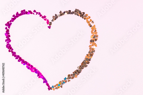 Happy Valentine's Day. Heart shape made of multicolored glitter. Heart made from shiny colorful sparkles on pink background. Love concept. Copy space. Top view