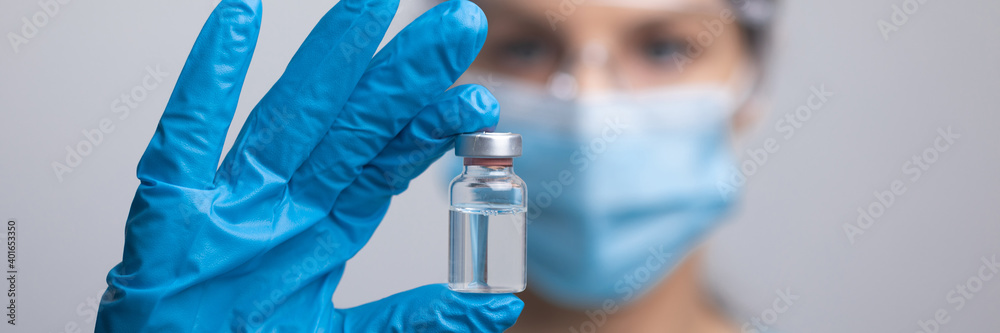 Doctor scientis in protective gloves and mask holding glass vial with injection liquid. Vaccination against influenza and coronavirus.