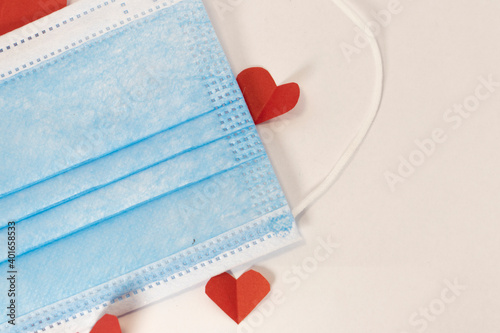 red heart on a mask on valentine's day on a white isolated background. heart surgical mask with place for inscription, mock up, copy space