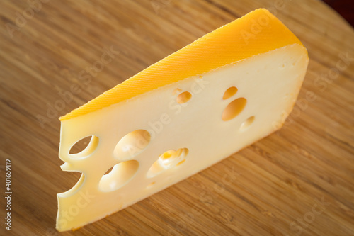 Yellow cow's milk Swiss cheese emmenthal with holes on wooden board..