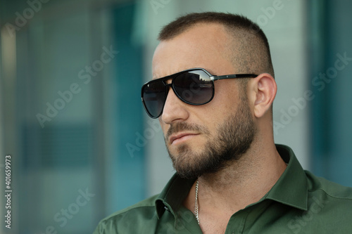 Sexy stylish man in sunglasses. City style. A beautiful and charming man with sunglasses outdoors. © lashkhidzetim