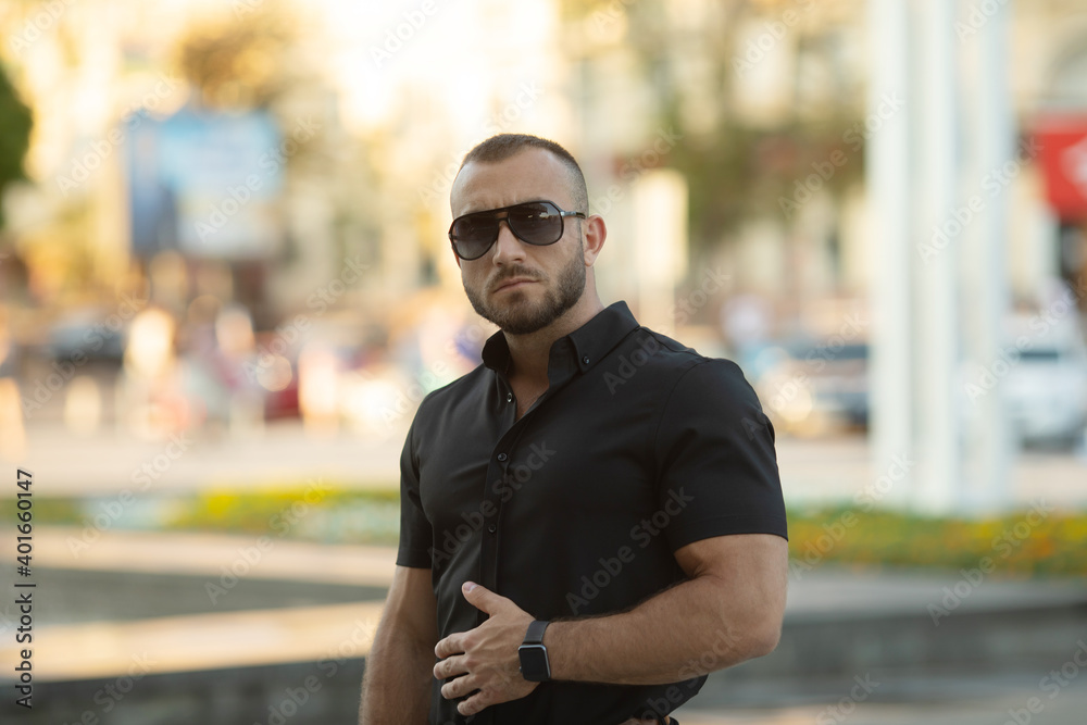 Fototapeta premium Sexy stylish man in sunglasses. City style. A beautiful and charming man with sunglasses outdoors.