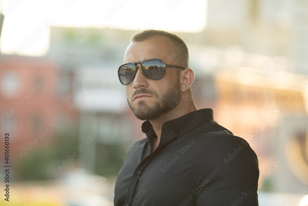 Sexy stylish man in sunglasses. City style. A beautiful and charming man with sunglasses outdoors. Sexy stylish man in sunglasses. City style. A beautiful and charming man with sunglasses outdoors.